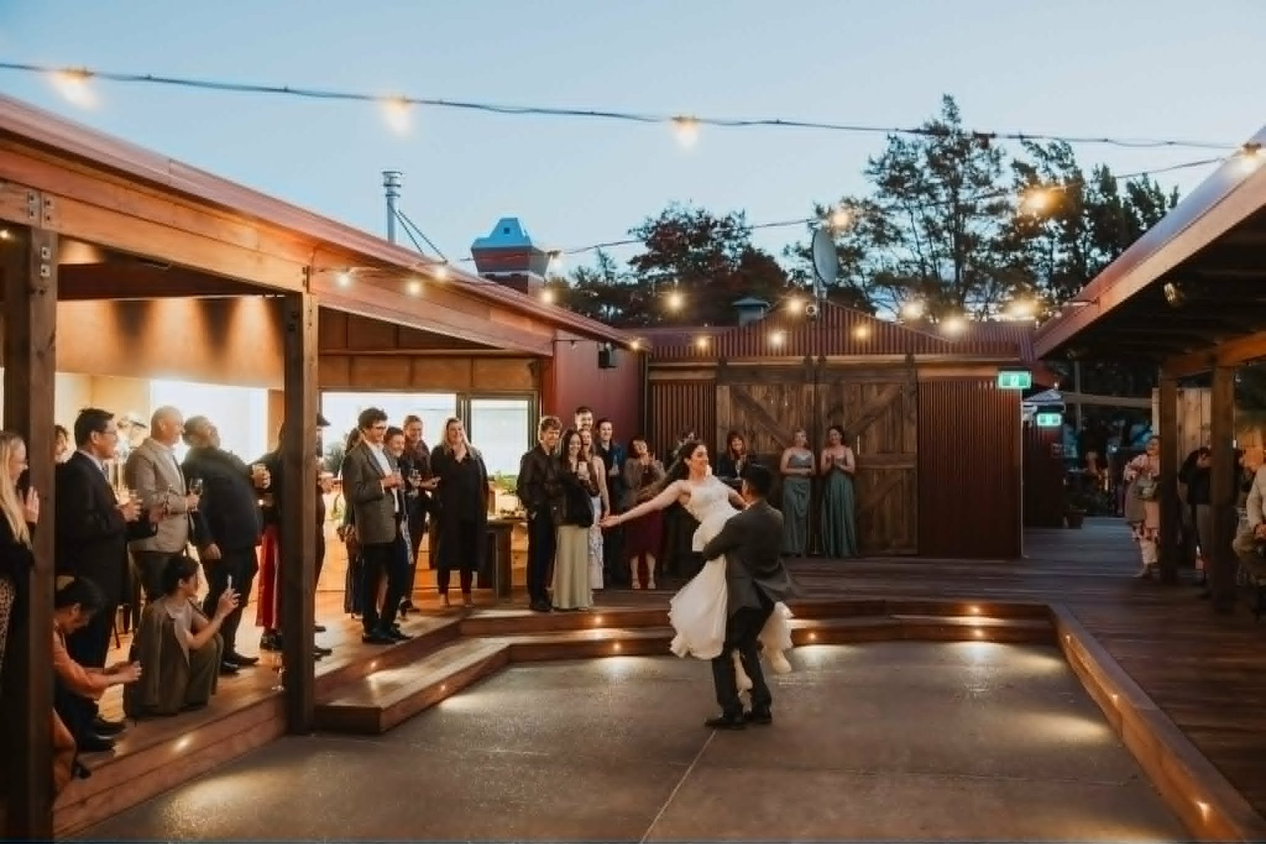 A couple dancing, guests circled around them under the lights